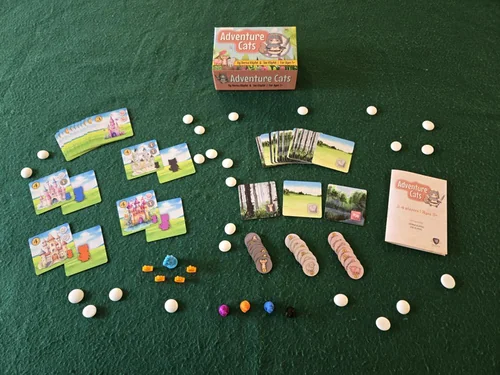 A game of Adventure Cats on green felt: animal tiles, gems, cat miniatures and castle cards.
