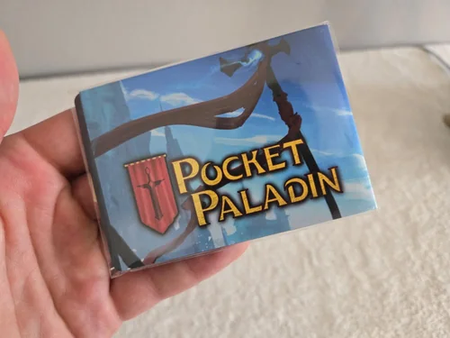 A hand holding the Pocket Paladin card box.